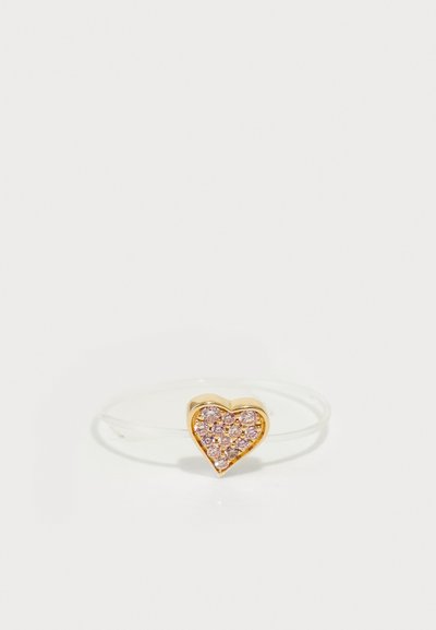 Gold heart-shaped ring featuring pink rhinestones, set on a thin, transparent band. Smooth surface with shiny accents.