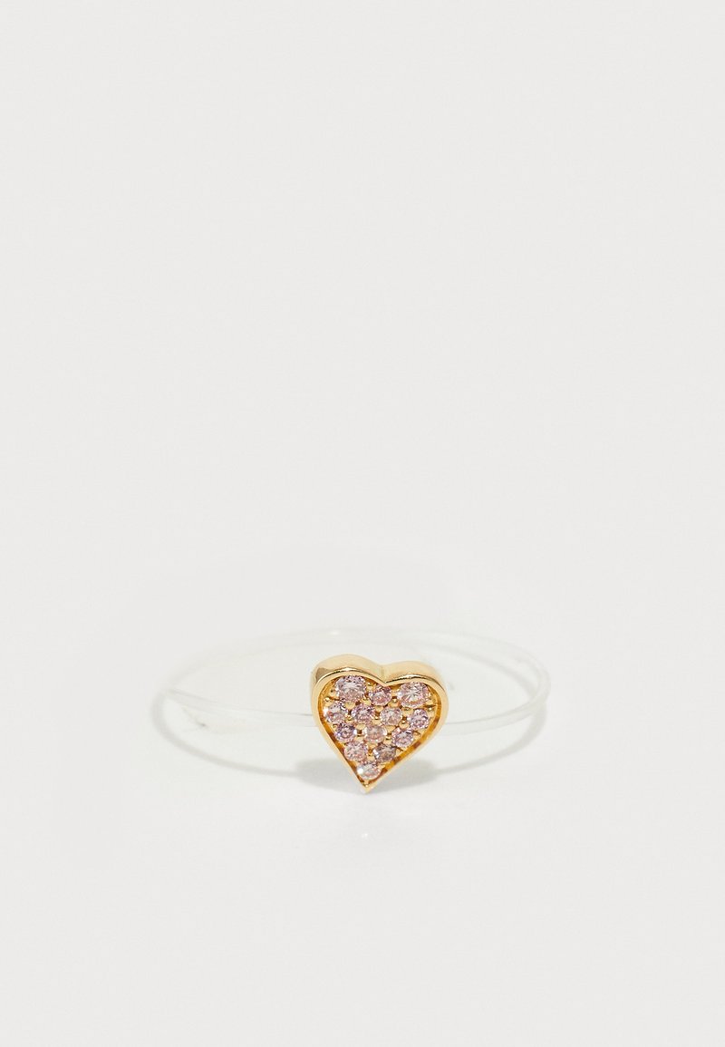 Anillo en forma de corazón dorado con rhinestones rosas, montado en una delgada banda transparente. Superficie suave con acentos brillantes.