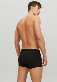 Schwarze Baumwoll-Boxershorts mit einem weichen, elastischen Bund. Niedrig geschnitten mit einer glatten Textur, ohne sichtbare Muster oder Verzierungen.