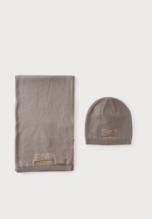 Ensemble écharpe et bonnet tricotés gris avec logo doré "EA7 Emporio Armani" sur fond blanc.