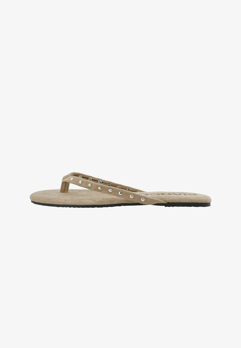 Tongs en daim beige avec clous métalliques sur les lanières et semelle noire, présentées en profil latéral sur fond blanc.