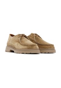 Zapatos de ante en un tono marrón claro con punta redondeada, parte delantera con cordones y costuras en contraste. Suela de goma gruesa y texturizada para mayor tracción.