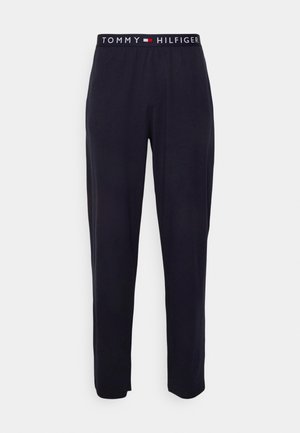 Pantalones de chándal azul marino con una textura suave y cinturilla elástica que presenta el logo 'TOMMY HILFIGER' en blanco y rojo. Corte recto.