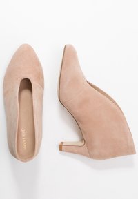 Beige suède wedge schoenen met een puntneus en een lage hak. De zool heeft een contrasterende bruine rubberen punt. Klassiek ontwerp, gladde textuur.