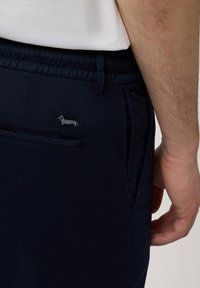 Navyblauwe broek van lichtgewicht stof met een elastische tailleband en zijzakken. Bevat een klein geborduurd teckel logo.