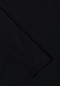 Sort ribstrikket stof, der viser et afsnit af et tøjstykke med en lang ærme. Tekstureret overflade med subtile sømme og en glat finish.