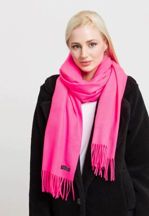 Sciarpa rosa brillante realizzata in materiale morbido, con bordi frangiati e un piccolo etichetta di marca. Indossata sopra un cappotto nero.
