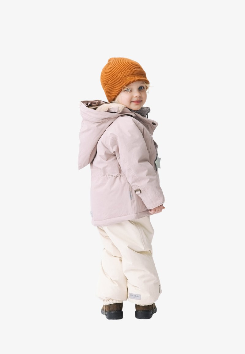 Gevoerde roze jas met grijze voering, voorzien van een sterdetail en capuchon, gecombineerd met een witte sneeuwbroek en een oranje geribde muts.