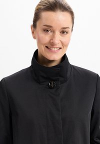 Schwarzer Mantel mit hohem Kragen, Ein-Knopf-Verschluss und glatter Textur. Einfaches Design betont die Funktionalität ohne sichtbare Muster.