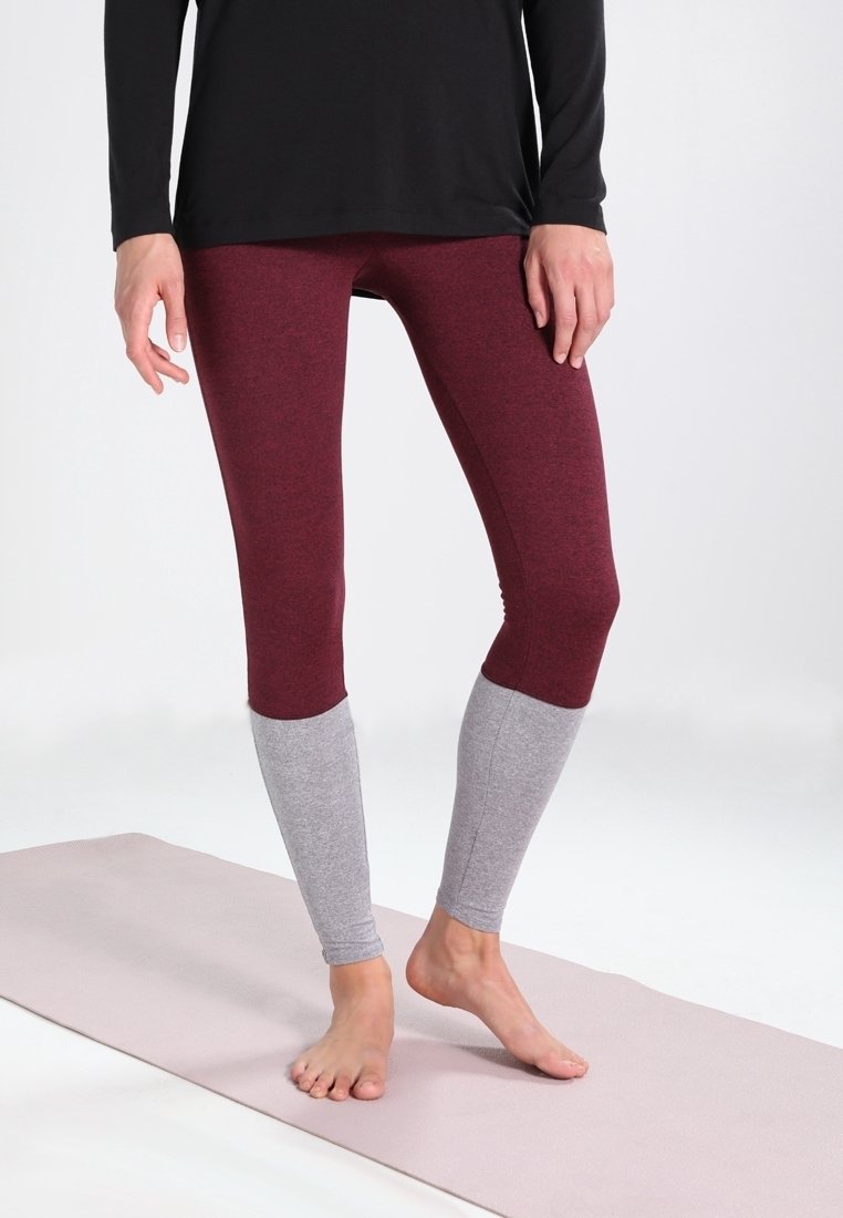 Leggings bordeaux con pannelli grigi inferiori, realizzati in tessuto elasticizzato, con una vestibilità aderente e una texture liscia, esposti con un top nero.