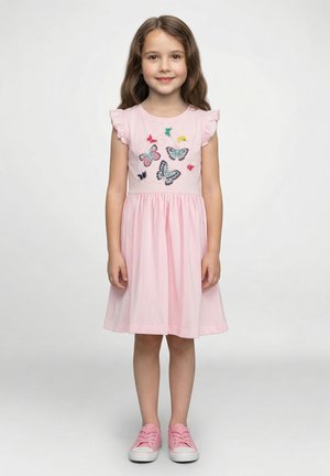 Rosa Baumwollkleid mit kurzen, gerafften Ärmeln und mehrfarbiger Schmetterlingsstickerei. Kombiniert mit pinken Turnschuhen.