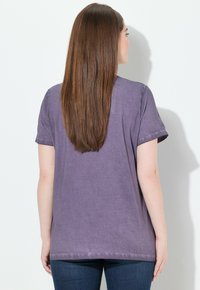 Camiseta de manga corta morada hecha de una tela suave, con un corte relajado y un dobladillo que cae justo por encima de las caderas.