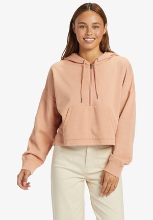 Rood gesneden roze hoodie van zachte stof met een voorkant zak, trekkoordcapuchon en geribde manchetten, gecombineerd met lichtgekleurde broek.