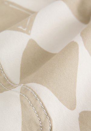 Bézs szövet mintás felülettel, fehér és világos bézs alakzatokkal. Látható varrás textúrát ad. Simas és puha anyag.