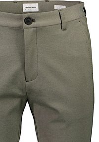 Schmal geschnittene, verkürzte Hosen aus olivgrünem Stoff mit glatter Textur, einem einzigen Knopfverschluss und Vorderseitentaschen.