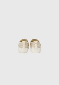 Canvas sneakers in ivory featuring a textured pattern and logo detail on the back. Flat white rubber sole for comfort and support.