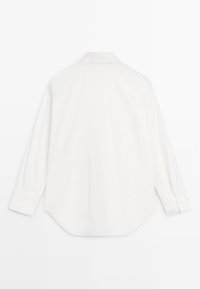 Chemise blanche à manches longues avec boutons, dos uni, col plié, poignets boutonnés, présentée à plat sur un fond blanc.