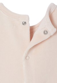 Nahaufnahme eines blassrosa, weichen Stoffs mit zwei silbernen Druckknöpfen, die teilweise am Ausschnitt eines Kleidungsstücks geschlossen sind.