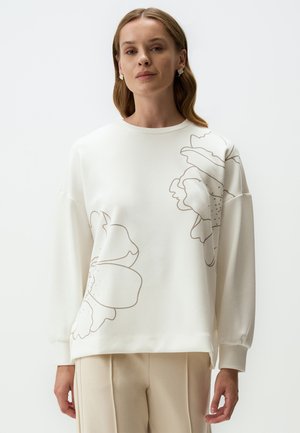 Felpa bianca con grandi stampe floreali beige, scollo rotondo e maniche lunghe. Tessuto morbido con una vestibilità leggermente larga. Visibili pantaloni abbinati.