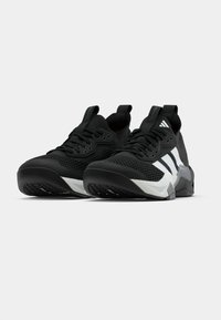 Ζευγάρι ασπρόμαυρων αθλητικών παπουτσιών με άνω μέρος από δίχτυ, κορδόνια  και θηλιές για τράβηγμα, σε λευκό φόντο.