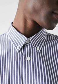 Striped shirt in navy and white, featuring a button-down collar and two white buttons visible at the neck. Smooth fabric texture.