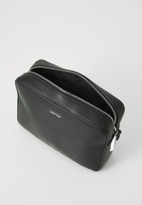 Black leather pouch with a rectangular shape, silver hardware, and double zipper. Features logo on the front and smooth texture.