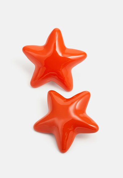 Two glossy, orange star-shaped objects, featuring five points, with a smooth and shiny surface. Each star is identical in design and color.
