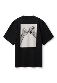 Černé tričko s černobílou fotografií dvou rukou, které si propleteny malíčky, symbolizující slib v čínské kultuře.