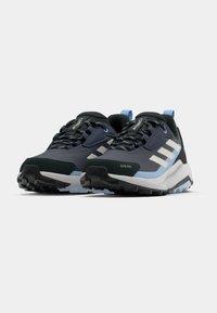 Σκούρα μπλε και μαύρα αθλητικά παπούτσια με λευκές λεπτομέρειες, υφασμένη επιφάνεια, στρογγυλή μύτη και ανθεκτική σόλα για πρόσφυση. Διαθέτουν κλείσιμο με κορδόνια.