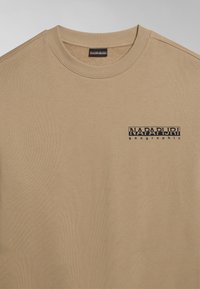 Felpa beige con collo tondo realizzata in cotone. Presenta un piccolo logo nero "NAPAPIJRI geographical" stampato sulla parte sinistra del petto. Texture liscia.