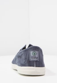 Mornarsko platneno slip-on čevlje z teksturirano površino in belo gumijasto podplatom. Ima zeleno-sivo oznako "naravni svet" na peti.