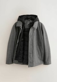 Chaqueta gris con capucha negra, con una tela exterior texturizada, cierre de botones y un forro interior acolchado, diseñada para ofrecer calidez y estilo.