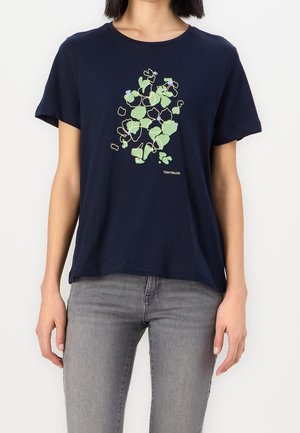 Mørkeblå bomulds t-shirt med korte ærmer, der har et grønt og blåt blomsterlineart-design. Løs pasform, rund halsudskæring.