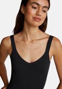 Černý bezrukávový body s hlubokým výstřihem ve tvaru V, s hladkým, elastickým povrchem. Jednoduchý design s širokými ramínky.