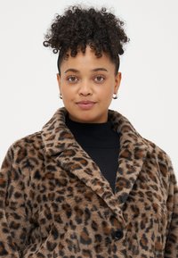 Palton din blană artificială cu imprimeu de leopard în nuanțe de brun și negru. Are o coloratură lată, închidere cu buton și o textură moale.