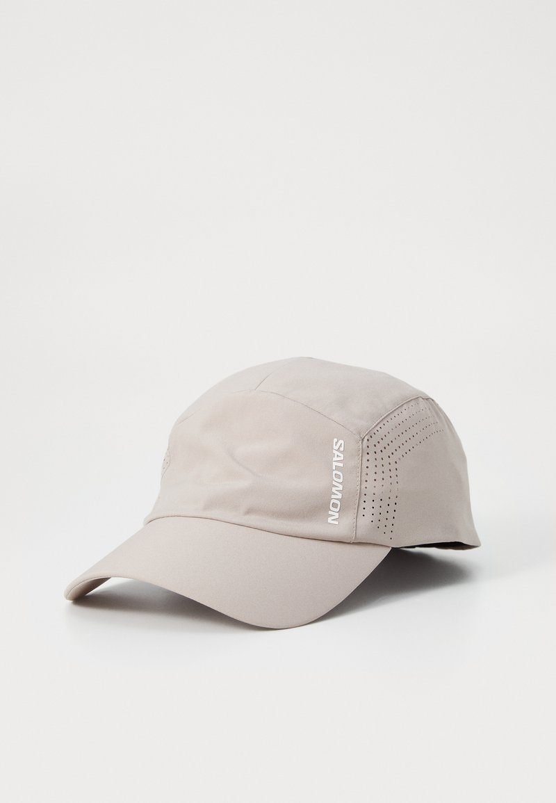 Light beige cap made of smooth fabric, featuring a curved brim, perforated detailing on the sides, and a white "SALOMON" logo.