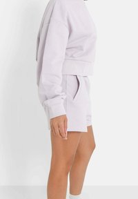 Ljuslila kort sweatshirt med långa ärmar, kombinerad med matchande shorts som har sidofickor och ett elastiskt midjeband.