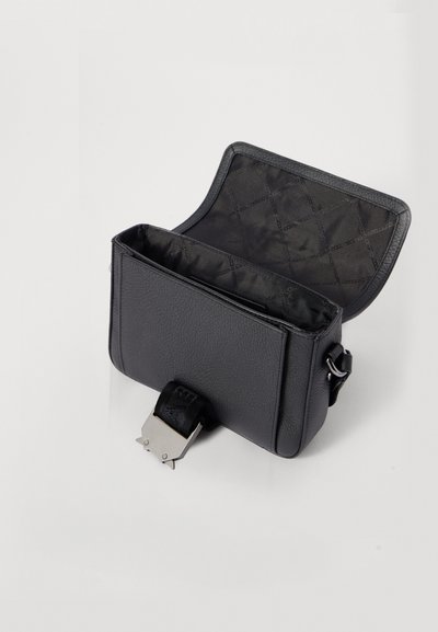 Sac en cuir noir avec un extérieur texturé, de forme rectangulaire et un fermoir en métal argenté. L'intérieur présente un motif matelassé.