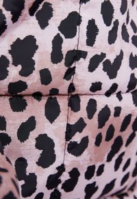 Wypełniony materiał w różowym i czarnym wzorze lamparta, o gładkiej teksturze i widocznym szyciu.