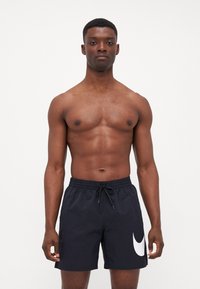 Costume da bagno nero con vita a cordoncino, caratterizzato da un grande logo Nike swoosh bianco sul lato sinistro inferiore. Tessuto dalla superficie liscia.