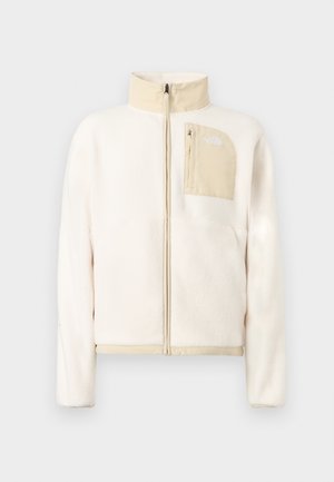 Cremefarbene Fleecjacke mit beigen Akzenten, durchgehendem Frontreißverschluss und einer mit Reißverschluss verschlossenen Brusttasche mit Logo auf einfarbigem Hintergrund.