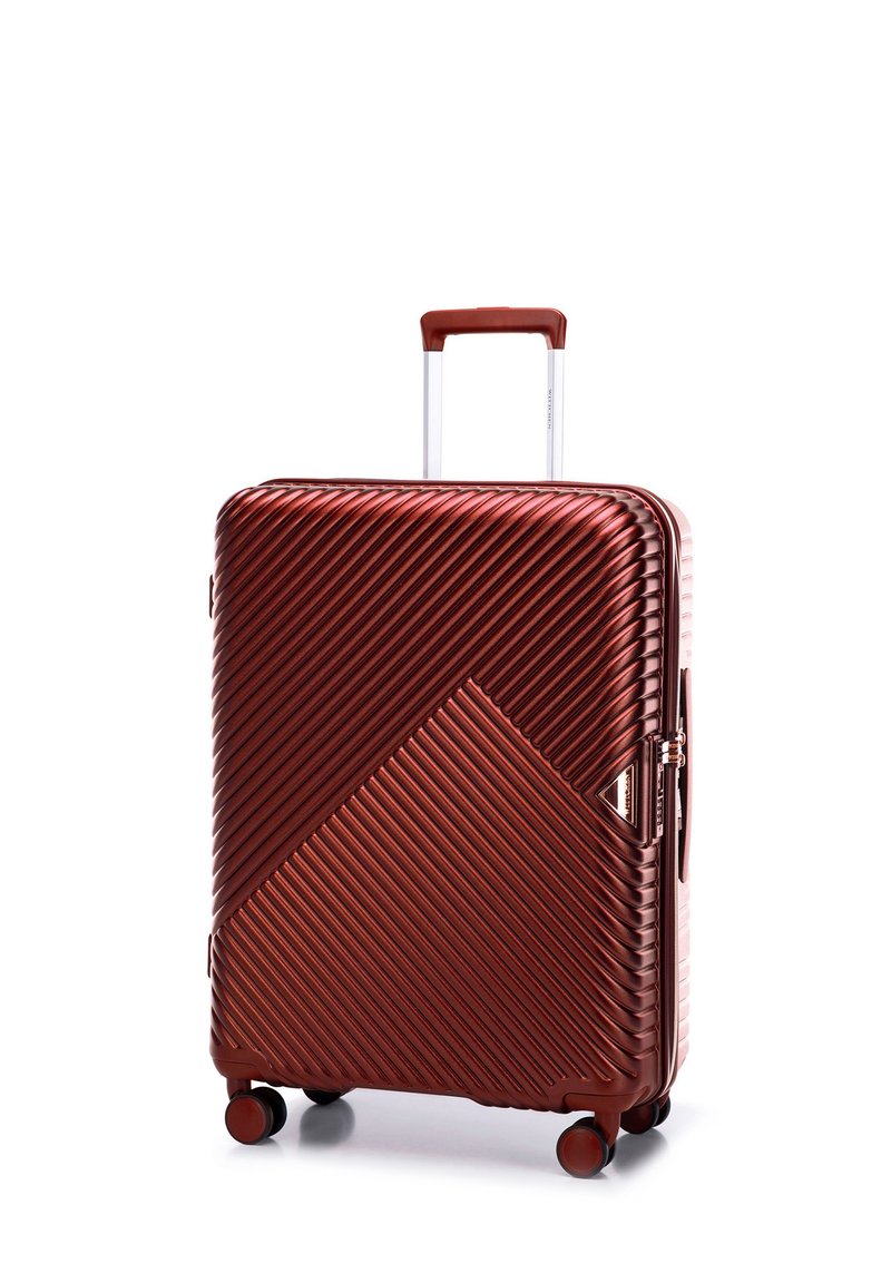 Valise rigide en cuivre métallisé, présentant une texture côtelée diagonale, une poignée rétractable et quatre roues pivotantes pour faciliter la mobilité.