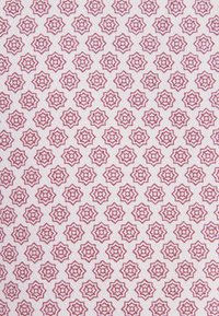 Motif répétitif d'étoiles à huit branches en rouge doux sur un fond de tissu blanc texturé, disposées en rangées et colonnes régulières.