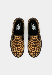 Cipele za klizanje s leopard uzorkom u crnoj i žutoj boji, s ravnim gumiranim potplatom i Vans logotipom unutar, s glatkim tekstilnim gornjim dijelom.