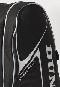 Borsa da golf nera realizzata in tessuto resistente con accenti bianchi. Caratterizzata da un design elegante, forma arrotondata e logo del marchio ben visibile.