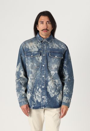 Denim shirt with a blue and white tie-dye pattern, featuring two chest pockets, snap buttons, and a logo on the left side.