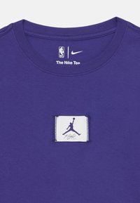 Vijolična bombažna majica z okroglim izrezom, logotipoma NBA in Nike ter belo etiketo z logotipom Jumpman in napisom "Flight".