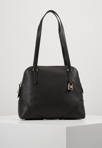 Sort læderhåndtaske med tekstureret finish, dobbelte håndtag, guldfarvet beslag, lynlåslukning og en lille vedhæng fastgjort på siden.