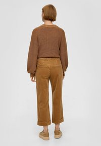 Bruine gebreide trui met raglanmouwen, gecombineerd met lichtbruine corduroy wijde broek. Casual schoeisel heeft een chunky platform.