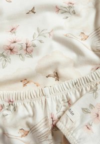 Bomuldsstof med en lys cremet baggrund prydet med blomster- og dyremotiver i bløde nuancer af pink, grøn og brun. Elastisk talje med mærke.